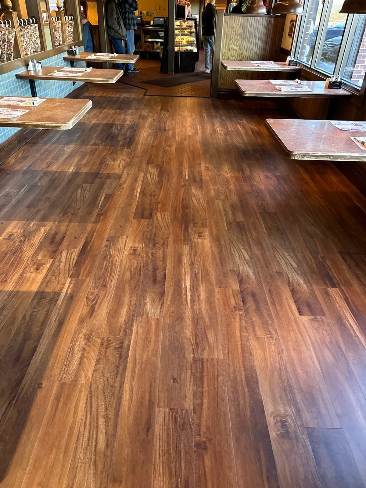Rich brown wood-look plank flooring installed in a restaurant dining area with tables and booths